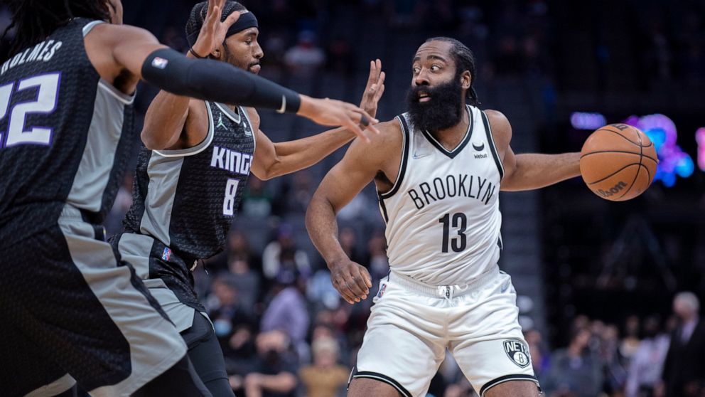 Brooklyn Nets guard James Harden (13) is double-teamed by Sacramento Kings forward Maurice Harkless (8) and center Richaun Holmes (22) during the first quarter of an NBA basketball game in Sacramento, Calif., Wednesday, Feb. 2, 2022. (AP Photo/José L