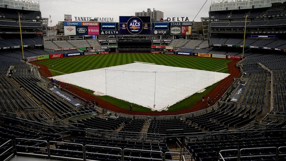 The rain tarp covers the field as a light rain falls on Yankee Stadium before Game 4 of an American League Championship baseball series between the New York Yankees and the Houston Astros, Sunday, Oct. 23, 2022, in New York. (AP Photo/Julia Nikhinson)
