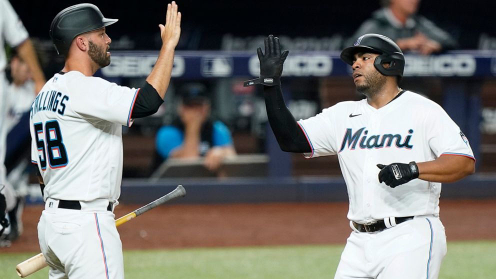 Miami Marlins' Jacob Stallings (58) and Jesus Aguilar congratulate each other after they both scored on a single by Jesus Sanchez during the second inning of a baseball game against the Seattle Mariners, Friday, April 29, 2022, in Miami. (AP Photo/Wi