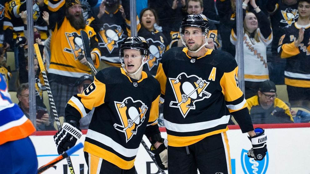 Jake Guentzel (59) is greeted by Brian Dumoulin (8) after scoring against the New York Islanders during the second period of an NHL hockey game Thursday, April 14, 2022, in Pittsburgh. (AP Photo/Keith Srakocic)
