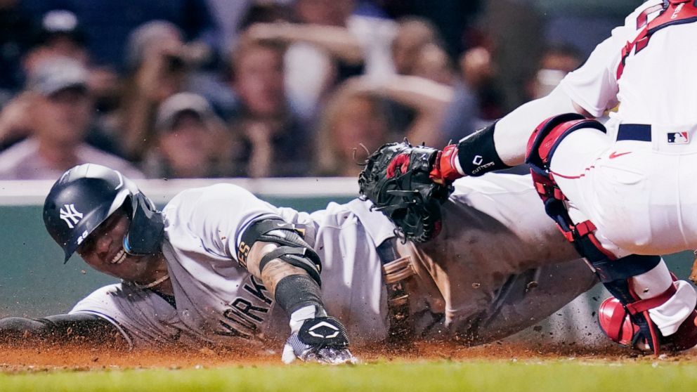 New York Yankees' Gleyber Torres smiles while sliding home safely on a throwing error by Boston Red Sox catcher Connor Wong, after driving in Aaron Judge and Aaron Hicks on a single, during the fifth inning of a baseball game at Fenway Park, Wednesda