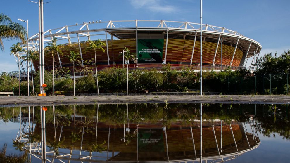 A venue at Olympic Park is reflected in a pool of water in the Barra da Tijuca western zone of Rio de Janeiro, Brazil, Thursday, June 24, 2021. With the Olympics about to kick off in Tokyo, the prior host is struggling to make good on legacy promises