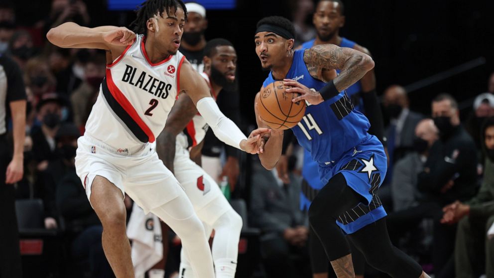 Orlando Magic guard Gary Harris,right, looks to pass the ball as Portland Trail Blazers forward Trendon Watford, left, defends during the first half of an NBA basketball game in Portland, Ore., Tuesday, Feb. 8, 2022. (AP Photo/Steve Dipaola)