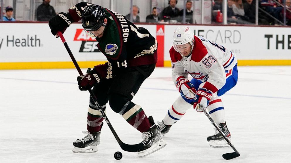 Arizona Coyotes' Shayne Gostisbehere (14) controls the puck in front of Montreal Canadiens' Evgenii Dadonov (63) in the second period during an NHL hockey game, Monday, Dec. 19, 2022, in Tempe, Ariz. (AP Photo/Darryl Webb)