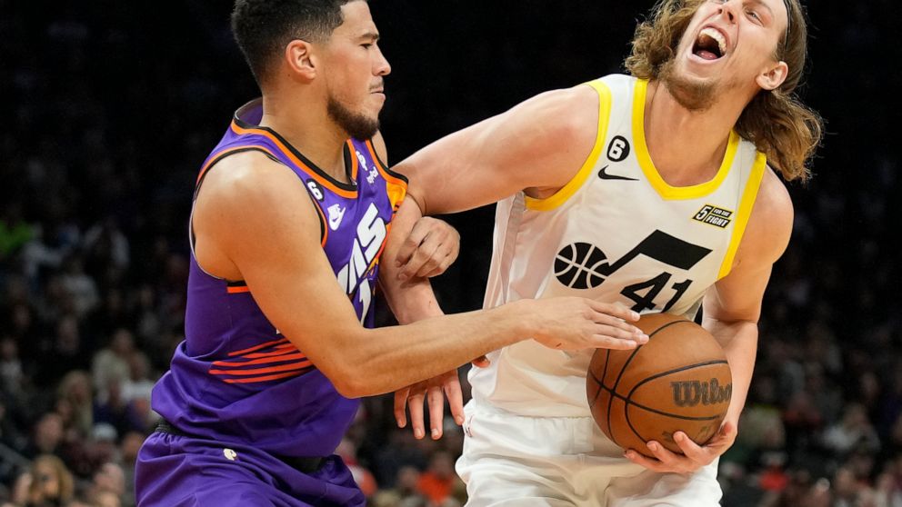 Utah Jazz forward Kelly Olynyk (41) gets fouled by Phoenix Suns guard Devin Booker during the first half of an NBA basketball game, Saturday, Nov. 26, 2022, in Phoenix. (AP Photo/Rick Scuteri)