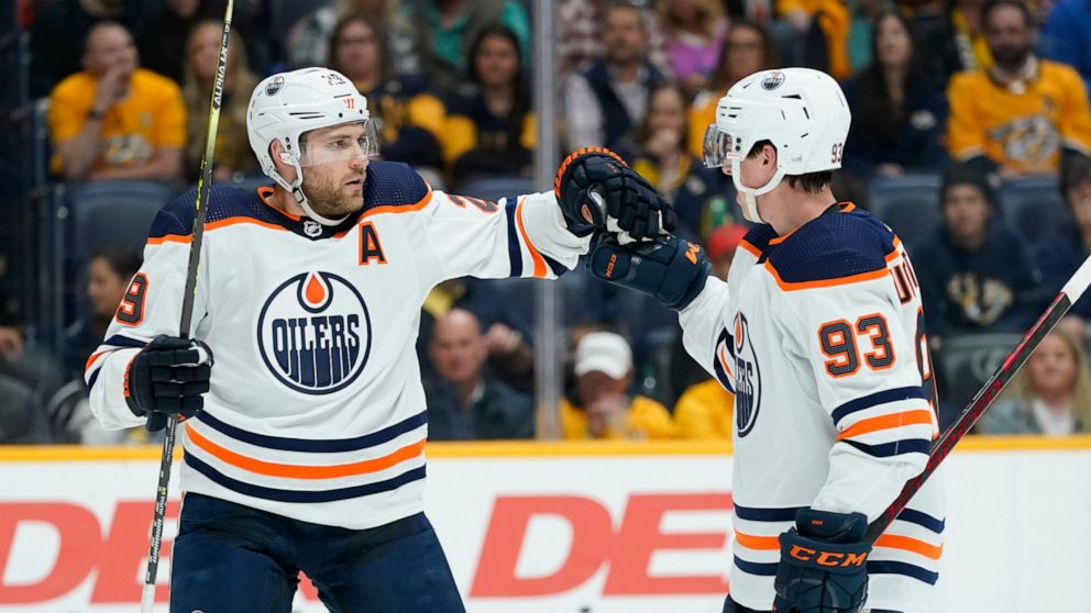 Edmonton Oilers' Leon Draisaitl (29) is congratulated by Ryan Nugent-Hopkins (93) after Draisaitl scored a goal against the Nashville Predators in the first period of an NHL hockey game Thursday, April 14, 2022, in Nashville, Tenn. (AP Photo/Mark Hum