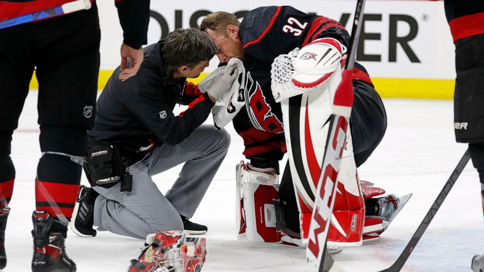 Carolina Hurricanes head athletic trainer Doug Bennett examines goaltender Antti Raanta (32) during the first period of Game 2 of the team's NHL hockey Stanley Cup first-round playoff series against the Boston Bruins in Raleigh, N.C., Wednesday, May 