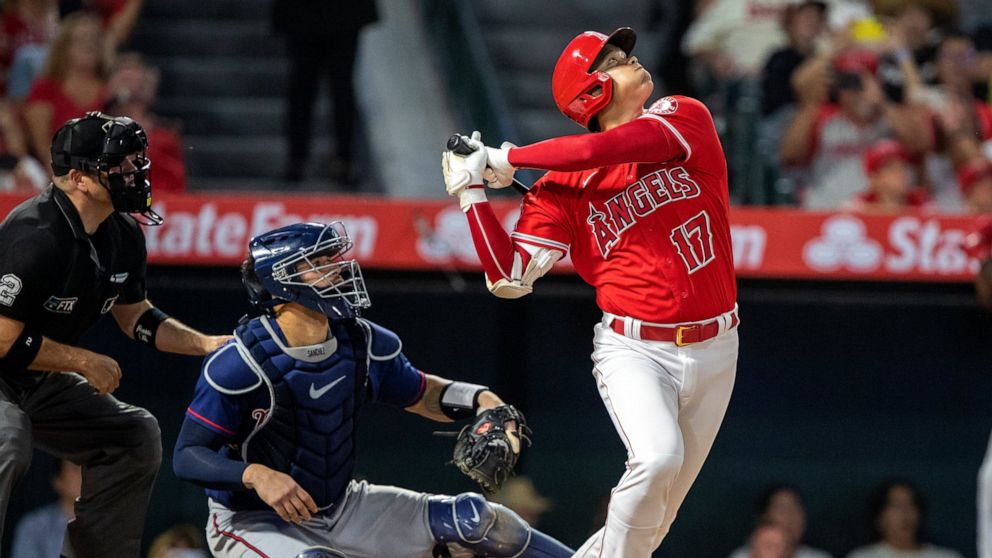 Los Angeles Angels designated hitter Shohei Ohtani, right, hits a pop fly for an out to Minnesota Twins third baseman Gio Urshela as Twins catcher Gary Sanchez, center, and home plate umpire Dan Bellino, left, look on during the sixth inning of a bas