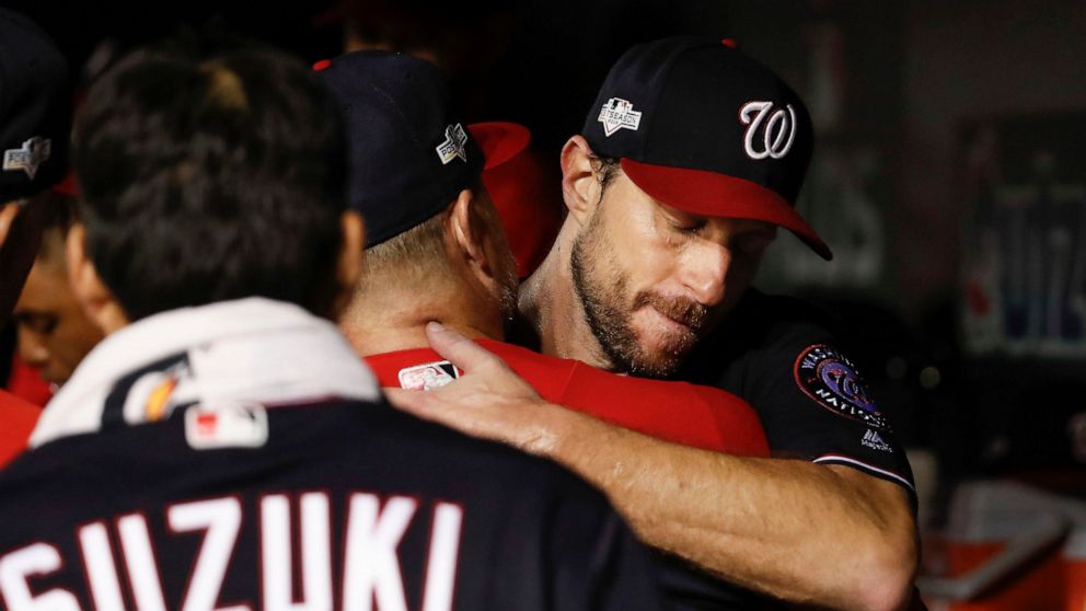 Washington Nationals starting pitcher Max Scherzer (31) is greeted by teammates in the dugout in the middle of the seventh inning in Game 4 of a baseball National League Division Series against the Los Angeles Dodgers, Monday, Oct. 7, 2019, in Washin
