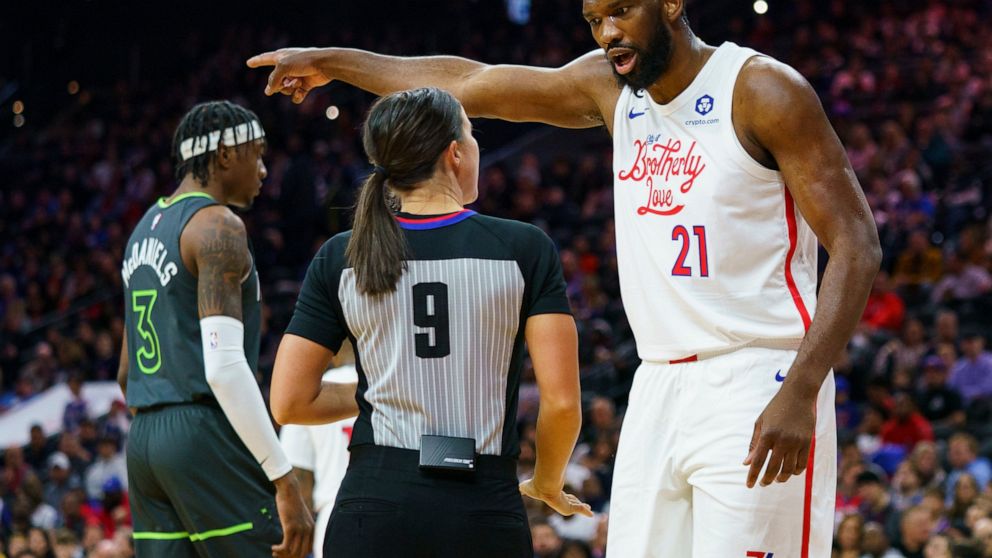 Philadelphia 76ers' Joel Embiid, right, reacts to a call by official Natalie Sago, center, during the first half of an NBA basketball game against the Minnesota Timberwolves, Saturday, Nov. 19, 2022, in Philadelphia. (AP Photo/Chris Szagola)