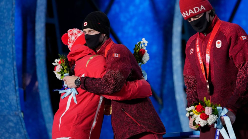 Silver medalist China's Su Yiming, left, embraces gold medalist Canada's Max Parrot during a medals ceremony for the men's snowboard slopestyle event at the 2022 Winter Olympics, Monday, Feb. 7, 2022, in Zhangjiakou, China. (AP Photo/Aaron Favila)