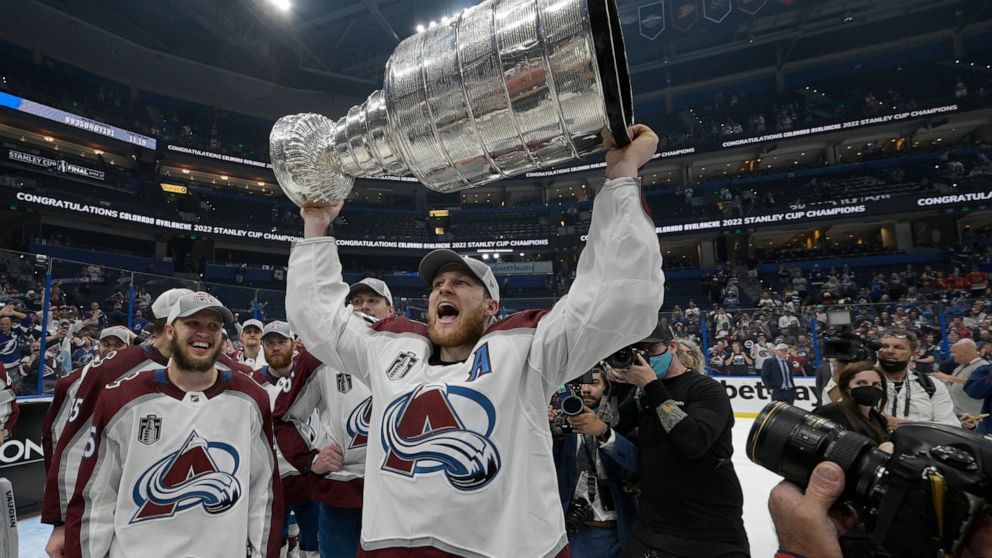 Colorado Avalanche center Nathan MacKinnon lifts the Stanley Cup after the team defeated the Tampa Bay Lightning in Game 6 of the NHL hockey Stanley Cup Finals on Sunday, June 26, 2022, in Tampa, Fla. (AP Photo/Phelan Ebenhack)