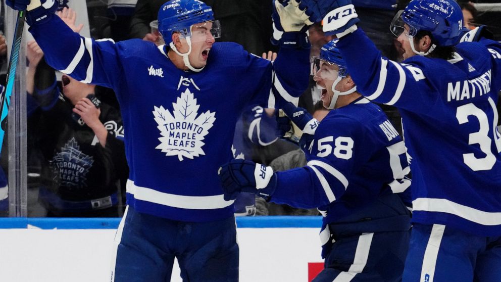 Toronto Maple Leafs' Justin Holl (3) celebrates his goal against the Ottawa Senators with tMichael Bunting and Auston Matthews during the third period of an NHL hockey game Saturday, Oct. 15, 2022, in Toronto. (Frank Gunn/The Canadian Press via AP)