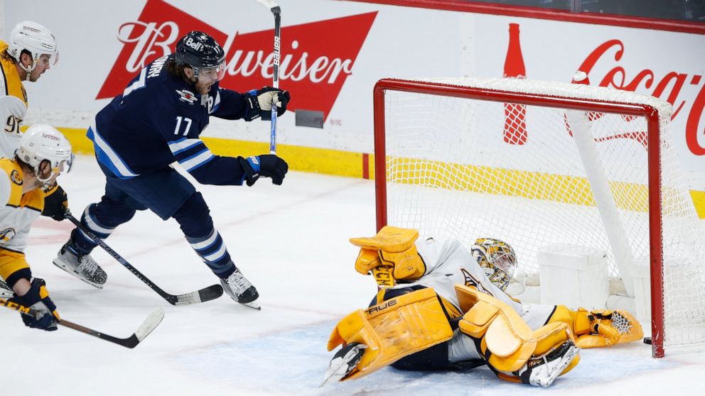Winnipeg Jets' Adam Lowry (17) celebrates as Kyle Connor's (not shown) shot sneaks through the pads of Nashville Predators goaltender Juuse Saros (74) for the winning goal during overtime in an NHL hockey game, Thursday, Dec. 15, 2022 in Winnipeg, Ma