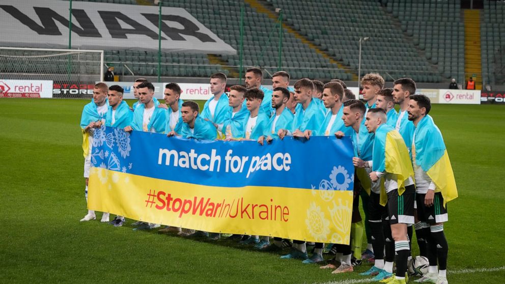 Team's players pose holding a banner before a friendly charity soccer match between Legia Warszawa and Dynamo Kyiv at the Polish Army Stadium in Warsaw, Poland, Tuesday, April 12, 2022. Ukrainian soccer club Dynamo Kyiv will play a series of charity 