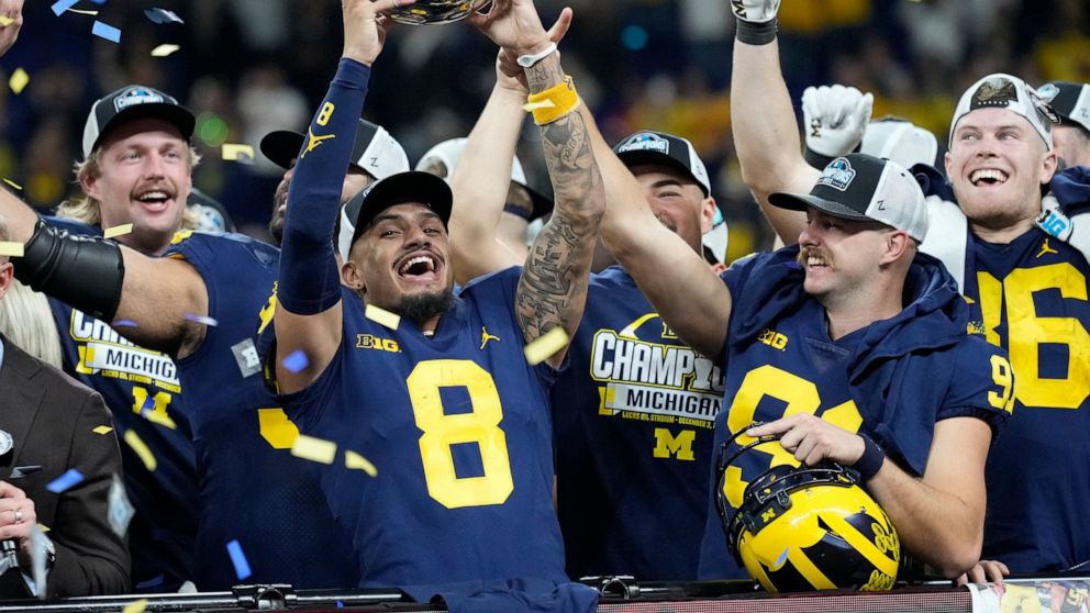 Michigan wide receiver Ronnie Bell holds the trophy as he celebrates with teammates after defeating Purdue in the Big Ten championship NCAA college football game, early Sunday, Dec. 4, 2022, in Indianapolis. Michigan won, 43-22. (AP Photo/AJ Mast)
