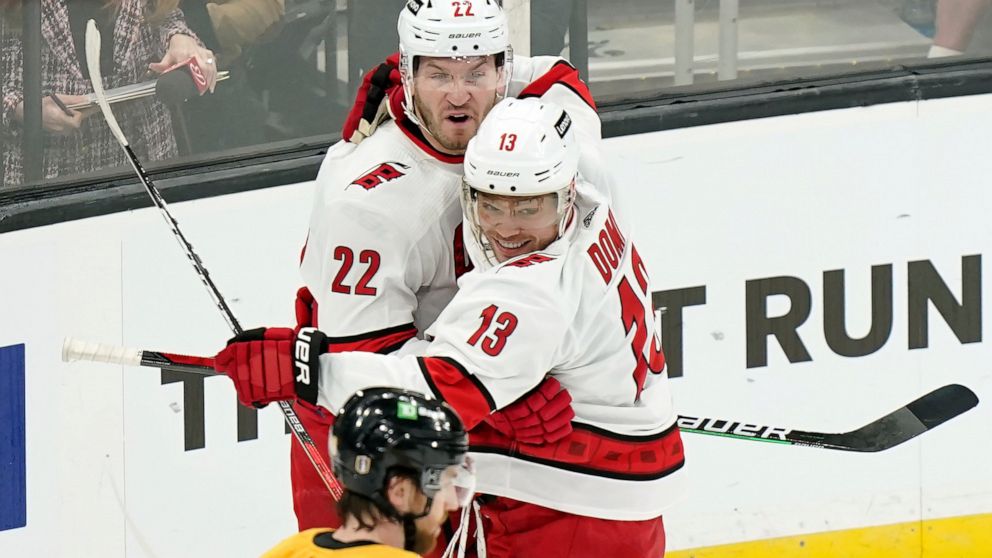 Carolina Hurricanes' Brett Pesce (22) celebrates his goal with Hurricanes' Max Domi (13) as Boston Bruins' Matt Grzelcyk, below, skates away in the first period of Game 4 of an NHL hockey Stanley Cup first-round playoff series, Sunday, May 8, 2022, i