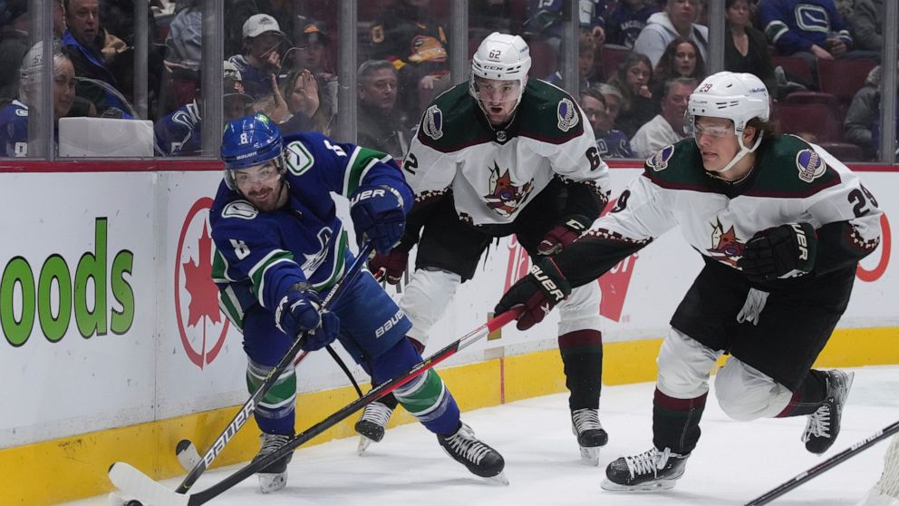 Vancouver Canucks' Conor Garland (8) vies for the puck against Arizona Coyotes' Barrett Hayton (29) as Janis Moser (62) watches during the first period of an NHL hockey game Thursday, April 14, 2022, in Vancouver, British Columbia. (Darryl Dyck/The C