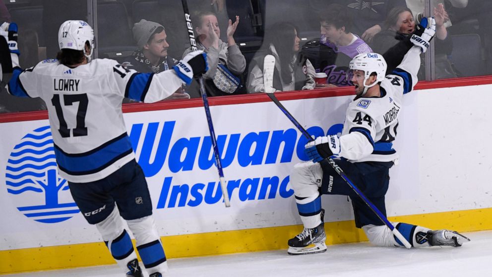 Winnipeg Jets' Josh Morrissey (44) celebrates after his winning goal against the Carolina Hurricanes with Adam Lowry (17) during overtime in NHL hockey game action in Winnipeg, Manitoba, Monday, Nov. 21, 2022. (Fred Greenslade/The Canadian Press via AP)