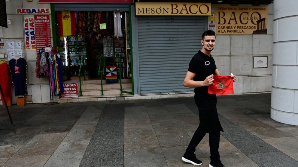 A man poses with a Moroccan flag in Spain's north African enclave of Ceuta, Monday, Dec. 5, 2022. The World Cup knockout game between Spain and Morocco on Tuesday will bring millions of fans on both sides of the Strait of Gibraltar together around sc