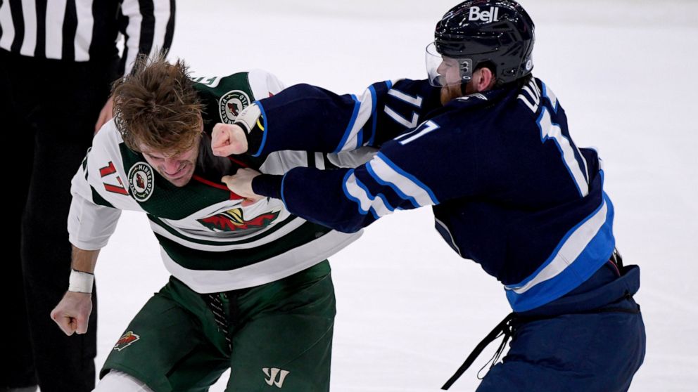 Winnipeg Jets' Adam Lowry (17) fights with Minnesota Wild's Marcus Foligno (17) during the third period of an NHL game in Winnipeg, Manitoba, Tuesday, Feb. 8, 2022. (Fred Greenslade/The Canadian Press via AP)