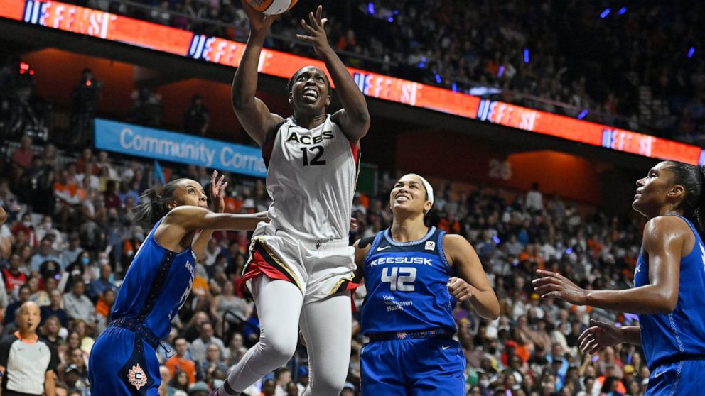 Las Vegas Aces' Chelsea Gray (12) goes up for a basket as Connecticut Sun's DeWanna Bonner, left, and Brionna Jones (42) defend during the second half in Game 4 of a WNBA basketball final playoff series, Sunday, Sept. 18, 2022, in Uncasville, Conn. (