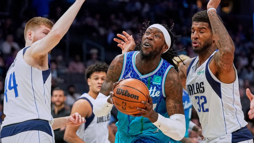 Charlotte Hornets center Montrezl Harrell, center, drives into the lane between Dallas Mavericks forwards Davis Bertans, left, and Marquese Chriss, right, during the first half of an NBA basketball game Saturday, March 19, 2022, in Charlotte, N.C. (A