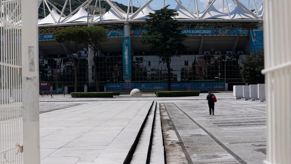 A man walks in front of Rome's Olympic stadium, Wednesday, June 9, 2021. The Euro 2020 gets underway on Friday June 11 and is being played in 11 host cities across 11 countries. (AP Photo/Alessandra Tarantino)