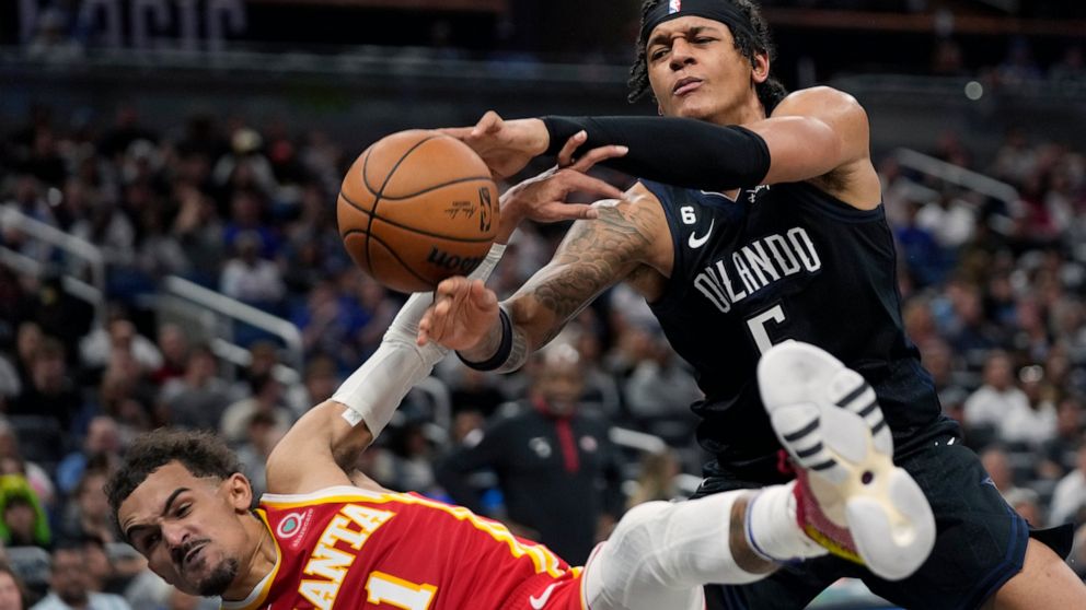 Atlanta Hawks' Trae Young, left, fouls Orlando Magic's Paolo Banchero (5) as he goes in for a shot during the second half of an NBA basketball game, Wednesday, Dec. 14, 2022, in Orlando, Fla. (AP Photo/John Raoux)
