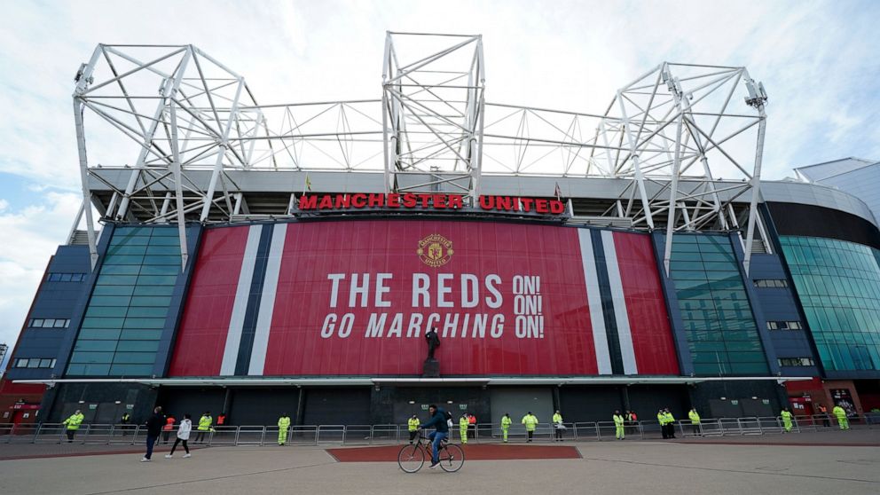 FILE - Security and stewards stand outside the Old Trafford stadium in Manchester, England, Tuesday, May 11, 2021 ahead of the English Premier League soccer match between Manchester United and Leicester City. Manchester United's American owners confi