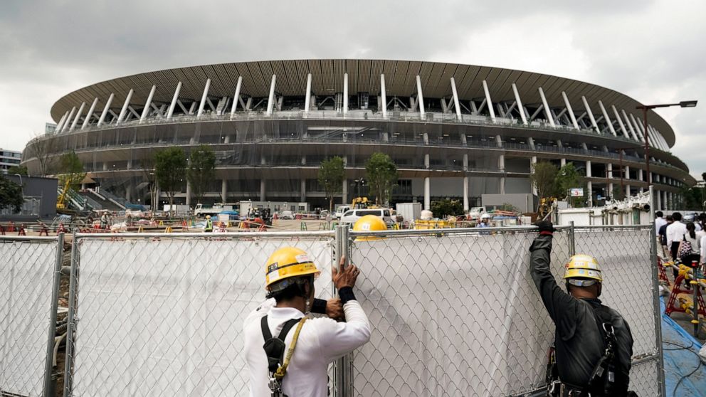 FILE - In this July 24, 2019, file, photo, workers adjust fences at the construction site of the New National Stadium, a venue for the opening and closing ceremonies at the Tokyo 2020 Olympics, in Tokyo. (AP Photo/Jae C. Hong, File)