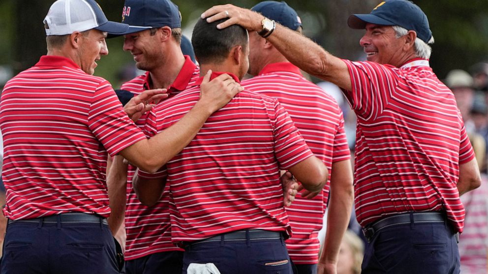 USA team members congratulate Xander Schauffele, center, on the 18th green after Schauffele won the hole and match during their singles match at the Presidents Cup golf tournament at the Quail Hollow Club, Sunday, Sept. 25, 2022, in Charlotte, N.C. T
