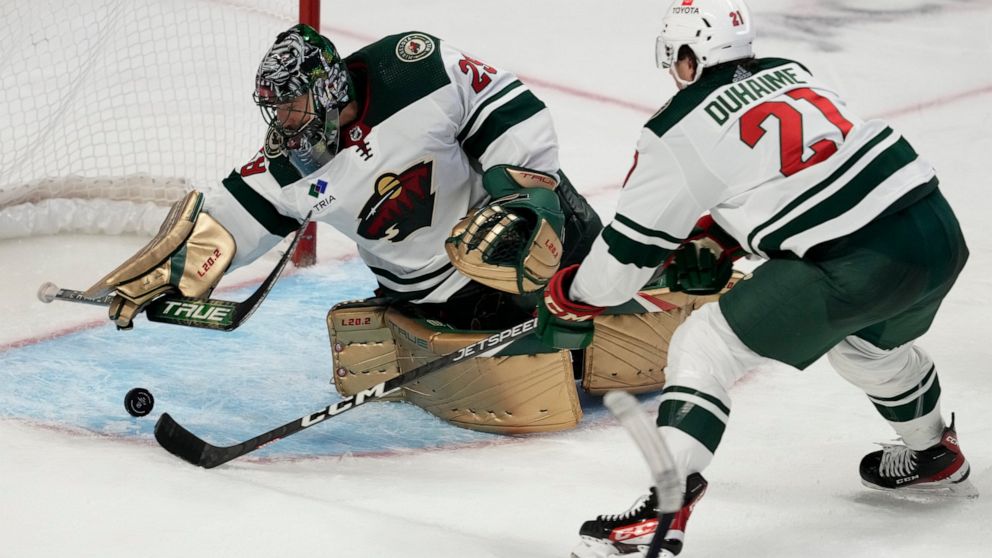 Minnesota Wild right wing Brandon Duhaime reaches for a loose puck as goaltender Marc-Andre Fleury reaches back to make a save during the third period of an NHL hockey game, Thursday, Oct. 27, 2022 in Ottawa, Ontario. (Adrian Wyld/The Canadian Press 