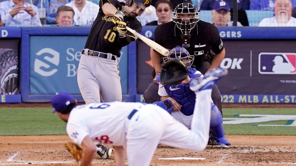 Pittsburgh Pirates' Bryan Reynolds, upper left, hits a two-run home run as Los Angeles Dodgers starting pitcher Mitch White, below, watches along with catcher Austin Barnes and home plate umpire Chad Fairchild during the fifth inning of a baseball ga