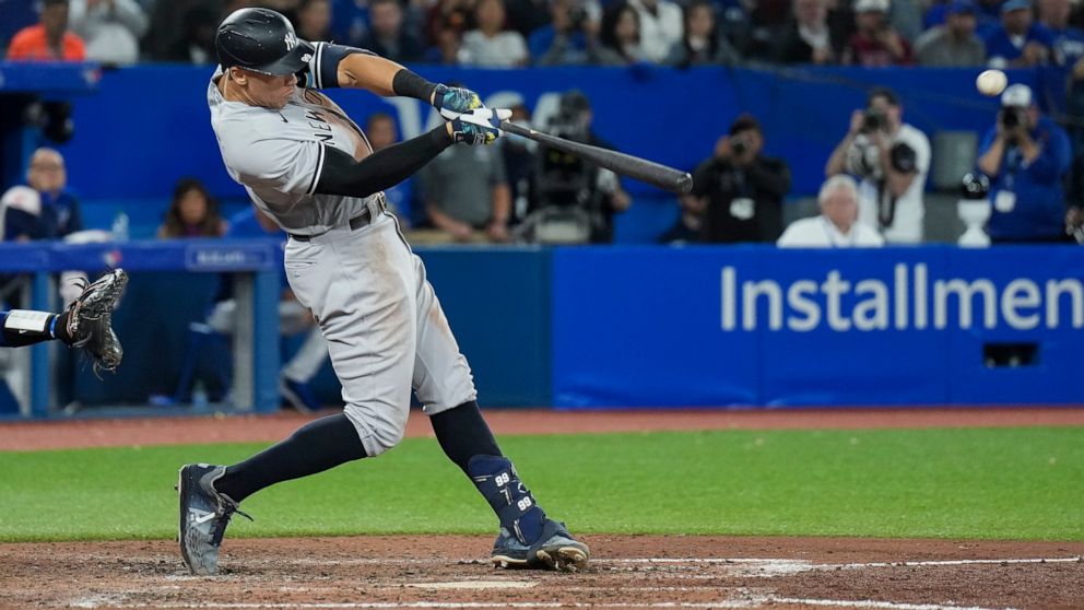 New York Yankees' Aaron Judge hits a two-run home run, his 61st homer of the season, during the seventh inning of the team's baseball game against the Toronto Blue Jays on Wednesday, Sept. 28, 2022, in Toronto. (Nathan Denette/The Canadian Press via AP)