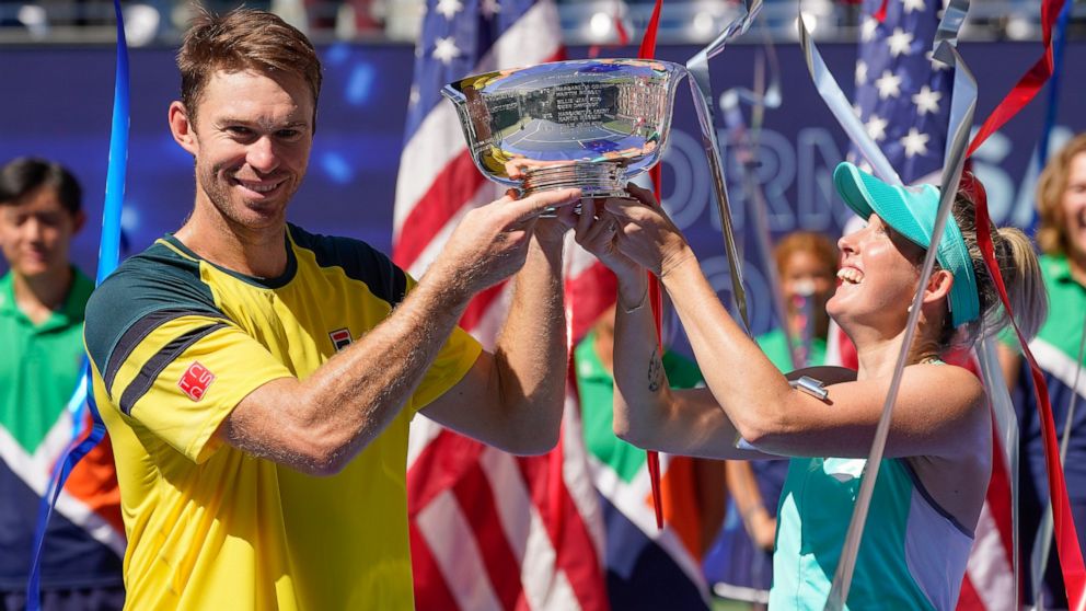 John Peers, left, and Storm Sanders, of Australia, hold up the championship trophy after winning the mixed doubles final against Kirsten Flipkens, of Belgium, and Edouard Roger-Vasselin, of France, at the U.S. Open tennis championships, Saturday, Sep