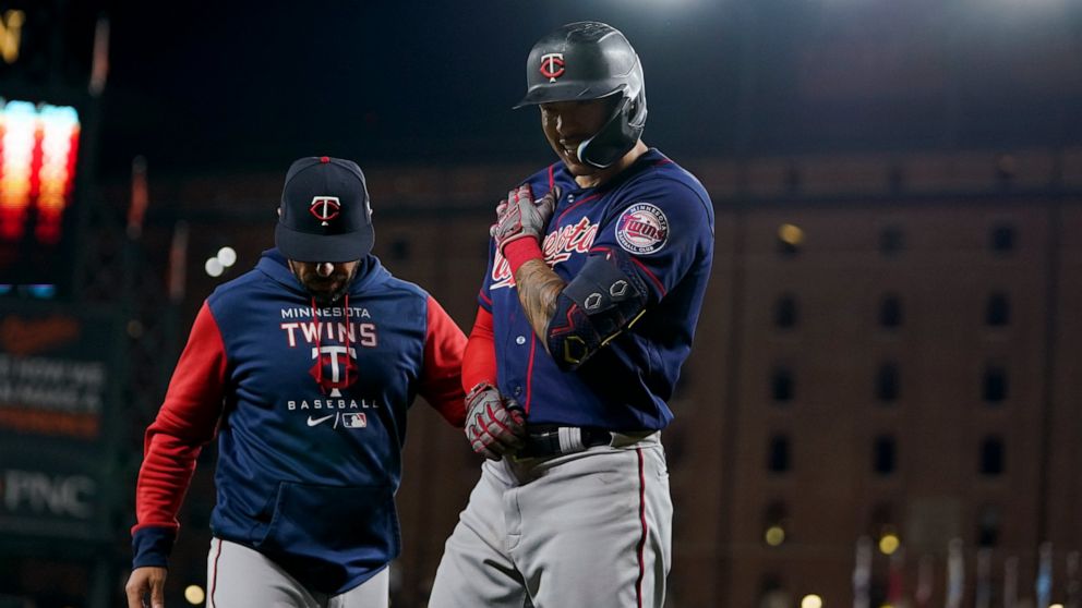 Minnesota Twins bench coach Jayce Tingler, left, stands next to Carlos Correa after he was hit by a pitch from Baltimore Orioles starting pitcher Spenser Watkins during the fifth inning of a baseball game, Thursday, May 5, 2022, in Baltimore. (AP Pho