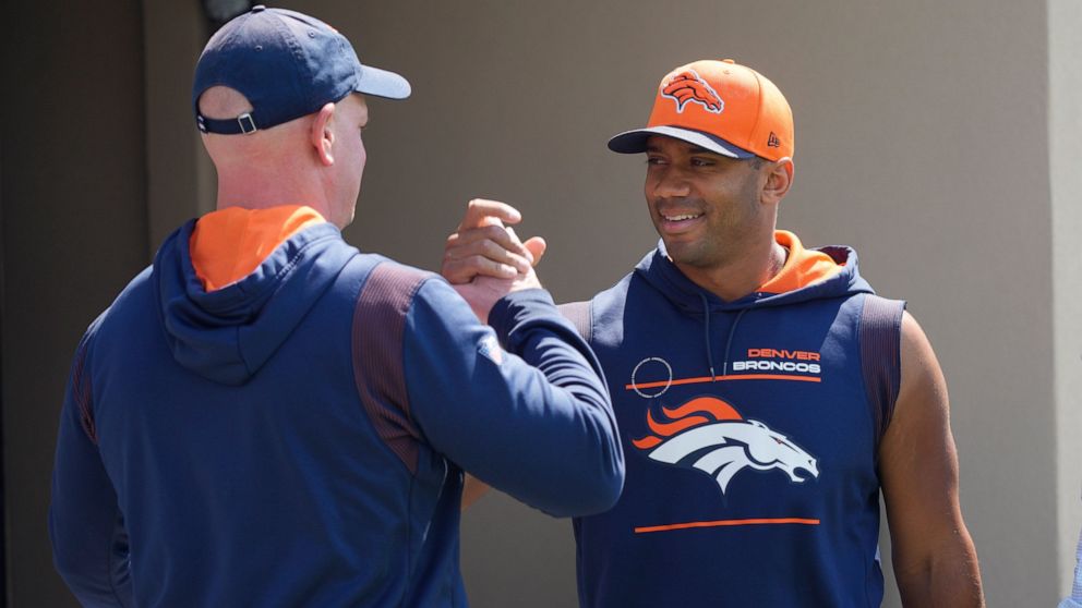 Denver Broncos head coach Nathaniel Hackett, left, greets quarterback Russell Wilson as he heads to a news conference before the NFL football team's practice Thursday, Sept. 8, 2022, at the Broncos' headquarters in Centennial, Colo. The Broncos open 