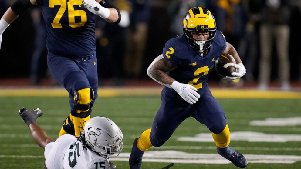 Michigan running back Blake Corum (2) escapes Michigan State safety Angelo Grose (15) in the first half of an NCAA college football game in Ann Arbor, Mich., Saturday, Oct. 29, 2022. (AP Photo/Paul Sancya)