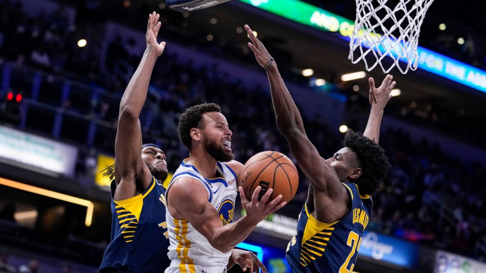 Golden State Warriors guard Stephen Curry (30) attempts a shot between Indiana Pacers center Myles Turner (33) and forward Aaron Nesmith (23) during the first half of an NBA basketball game in Indianapolis, Wednesday, Dec. 14, 2022. (AP Photo/Michael