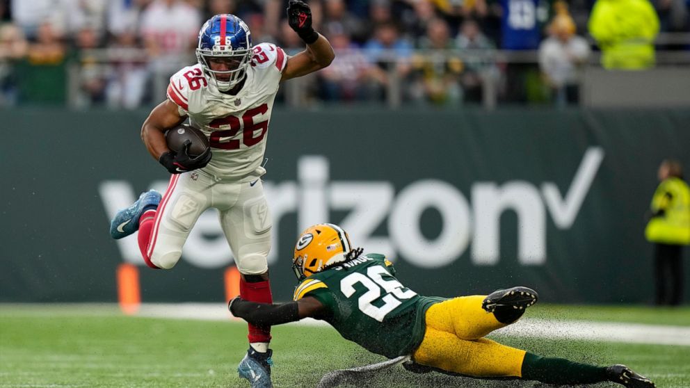 New York Giants running back Saquon Barkley (26) breaks away from Green Bay Packers safety Darnell Savage (26) for a touchdown during the second half of an NFL football game at the Tottenham Hotspur stadium in London, Sunday, Oct. 9, 2022. (AP Photo/