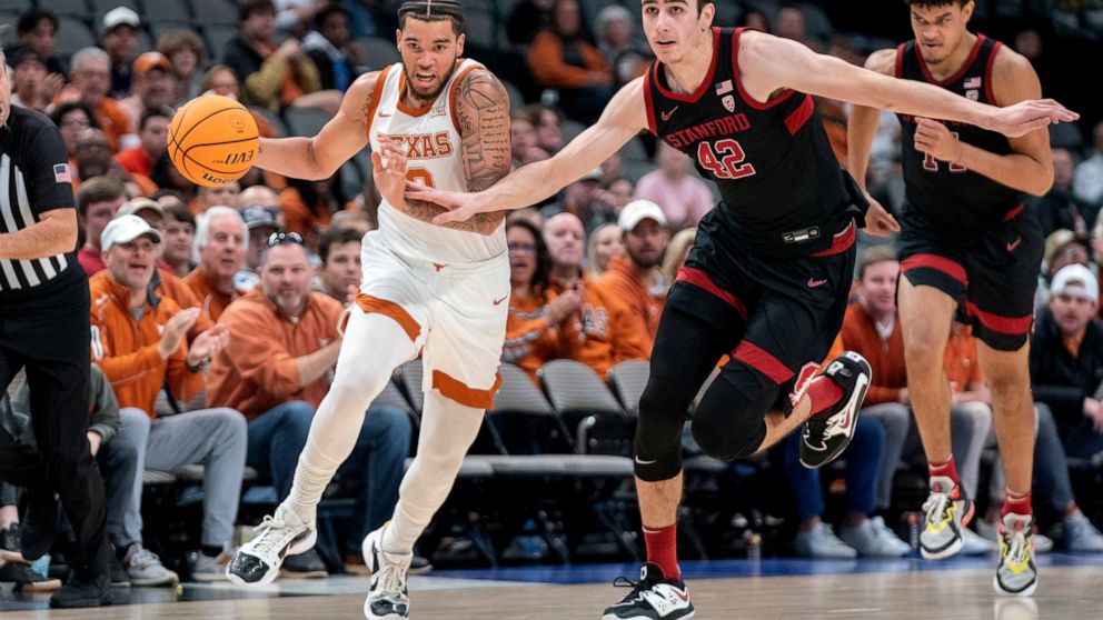 Texas forward Timmy Allen (0) drives past Stanford forward Maxime Raynaud (42) on a fast break during the first half of an NCAA college basketball game, Sunday, Dec. 18, 2022, in Dallas. (AP Photo/Jeffrey McWhorter)