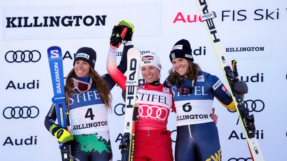 Switzerland's Lara Gut-Behrami, first place, center, and Italy's Marta Bassino, second place, left, and Sweden's Sara Hector, third place, acknowledge applause on the podium following a World Cup giant slalom skiing race Saturday, Nov. 26, 2022, in K
