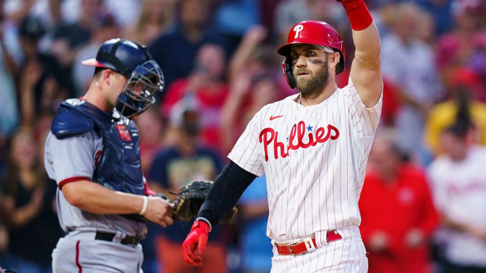 Philadelphia Phillies' Bryce Harper, right, reacts to his two-run home run, next to Washington Nationals catcher Riley Adams during the third inning of a baseball game Saturday, Sept. 10, 2022, in Philadelphia. (AP Photo/Chris Szagola)