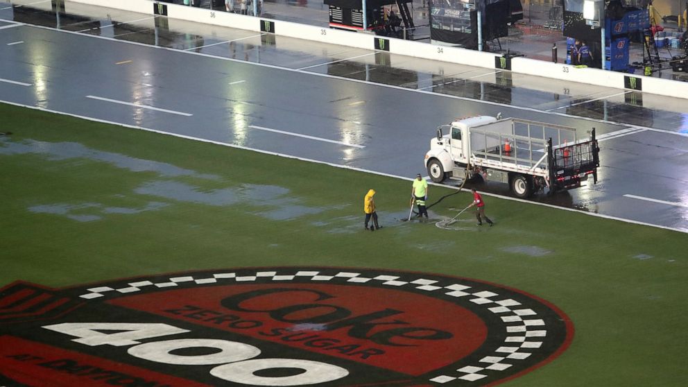 Track workers attempt to clear some of the water off of the infield grass as rain falls before a NASCAR Cup Series auto race at Daytona International Speedway, Saturday, Aug. 27, 2022, in Daytona Beach, Fla. (AP Photo/David Graham)