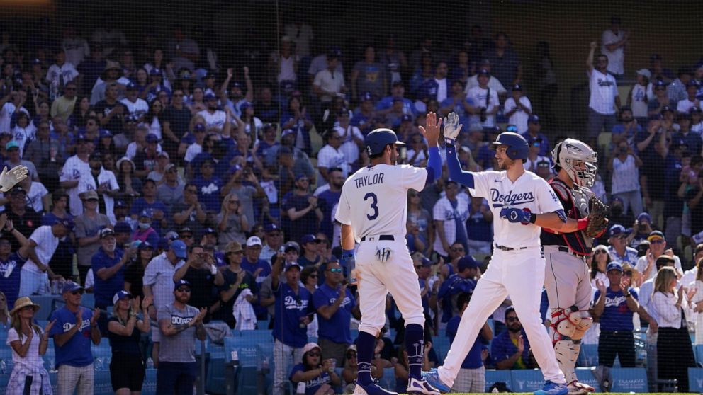 Los Angeles Dodgers' Trea Turner, center, is congratulated by Chris Taylor, left, after hitting a two-run home run as Cleveland Guardians catcher Austin Hedges stands at the plate during the second inning of a baseball game Saturday, June 18, 2022, i