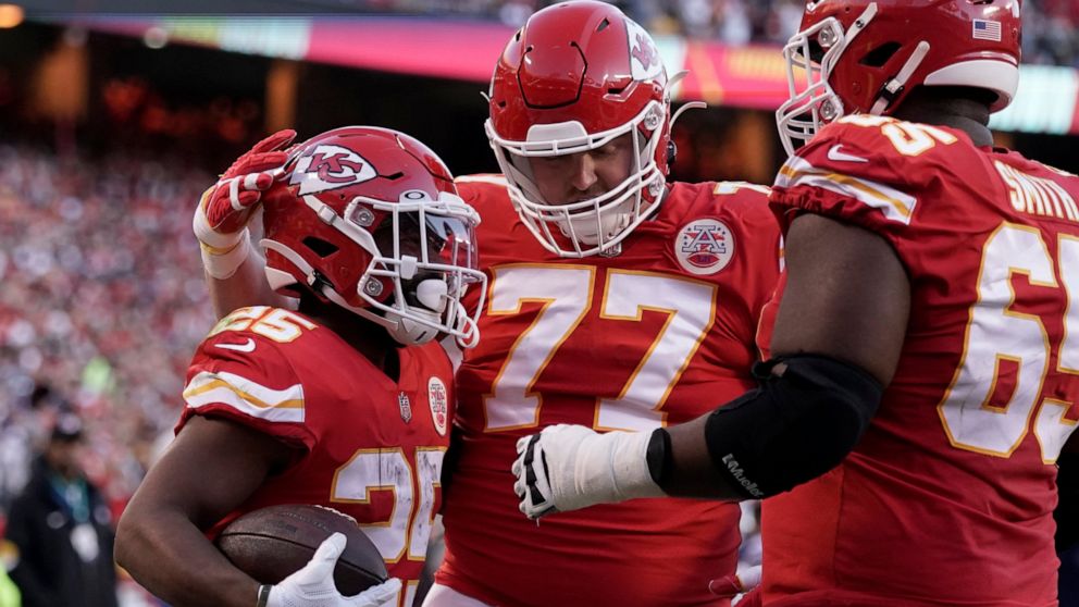 Kansas City Chiefs running back Clyde Edwards-Helaire, left, is congratulated by Andrew Wylie (77) and Trey Smith (65) after scoring during the first half of an NFL football game against the Dallas Cowboys Sunday, Nov. 21, 2021, in Kansas City, Mo. (