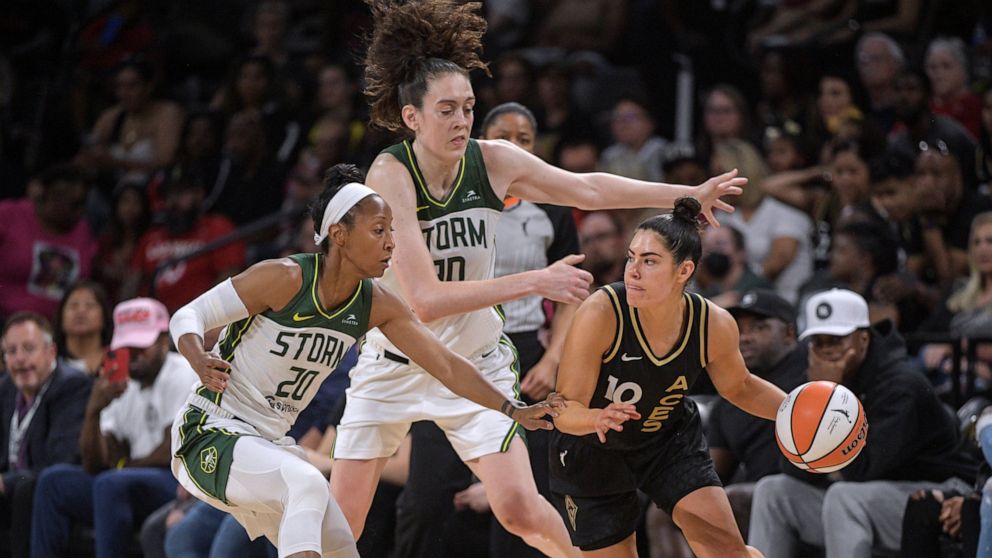 Las Vegas Aces guard Kelsey Plum (10) is defended by Seattle Storm guard Briann January (20) and forward Breanna Stewart (30) during the second half of a WNBA game Sunday, Aug. 14, 2022, in Las Vegas. (AP Photo/Sam Morris)
