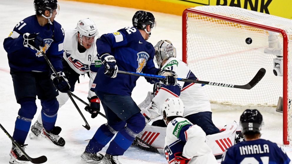 Finland's Valtteri Filppula, left, Harri Pesonen, center, and Jere Innala, right, attempt to score against goalkeeper Strauss Mann of USA during the 2022 IIHF Ice Hockey World Championships preliminary round group B match between Finland and USA in T