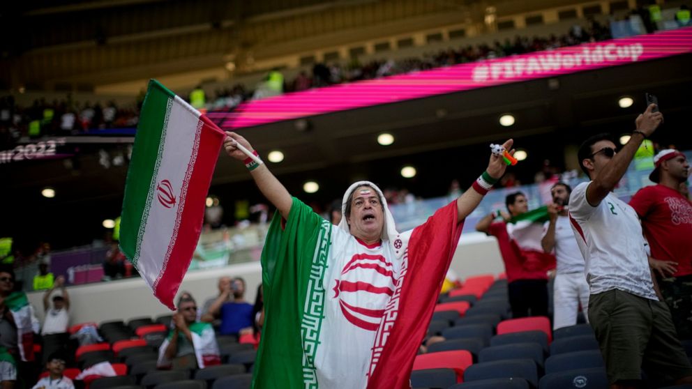 A soccer fan holds a flag from Iran prior to the World Cup group B soccer match between Wales and Iran, at the Ahmad Bin Ali Stadium in Al Rayyan , Qatar, Friday, Nov. 25, 2022. (AP Photo/Francisco Seco)